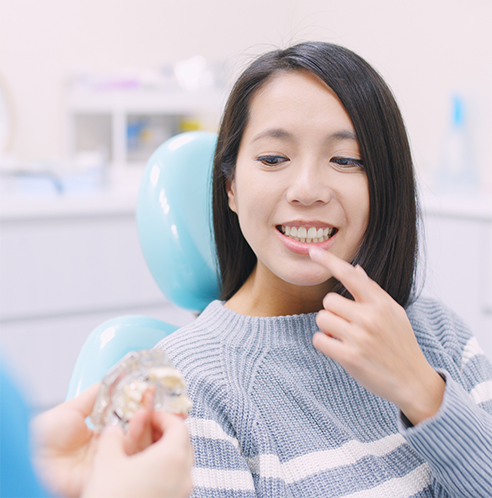 Female patient looking at dental implant guide while pointing to teeth
