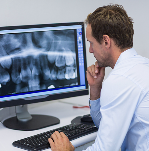 Dentist looking at dental X-rays on computer monitor