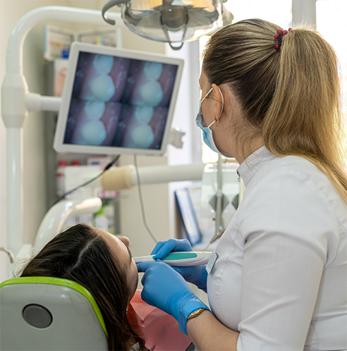 Female dentist looking at patient's teeth with intraoral camera