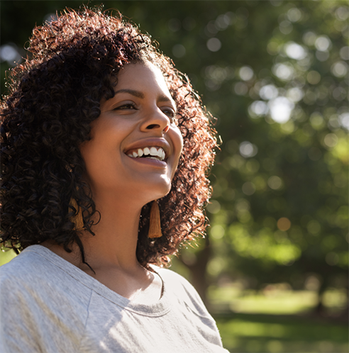 Woman with curly hair smiling outside