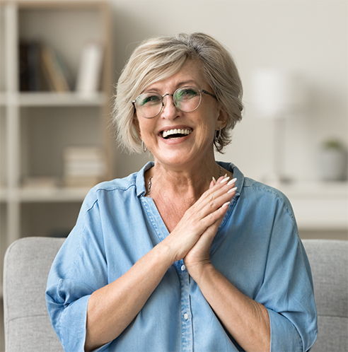 Senior woman with glasses smiling on couch