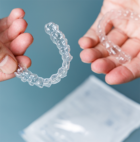 Hands holding clear aligners