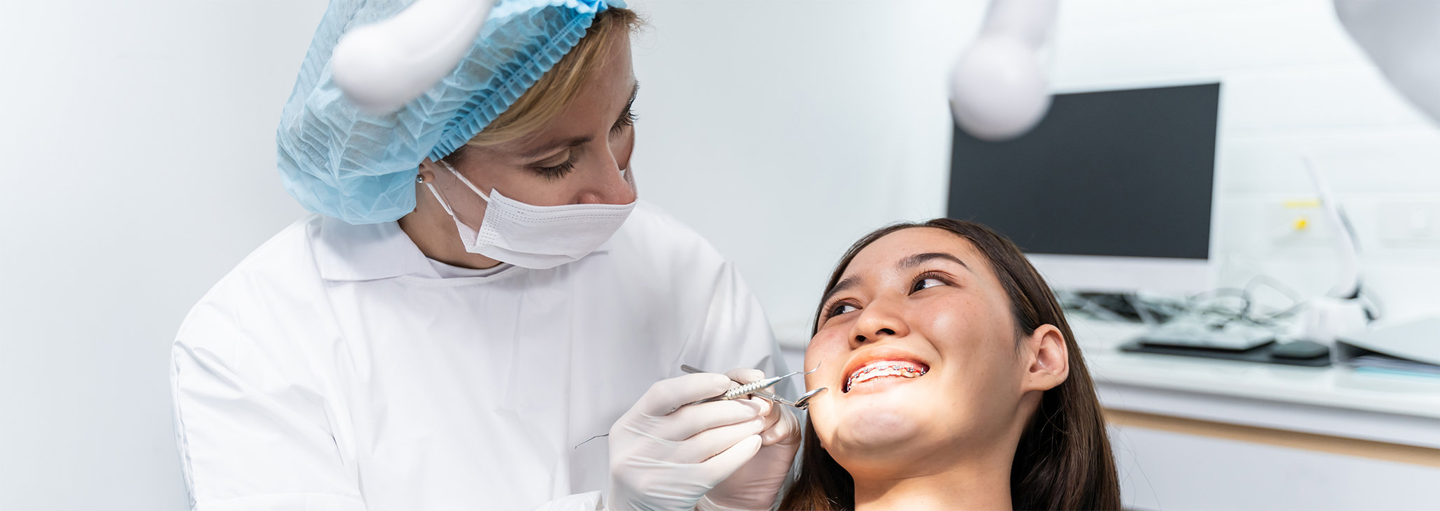 Woman with braces smiling up at dentist during dental checkup in Midland