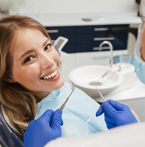 Female patient smiling at dentist holding instruments for cleaning