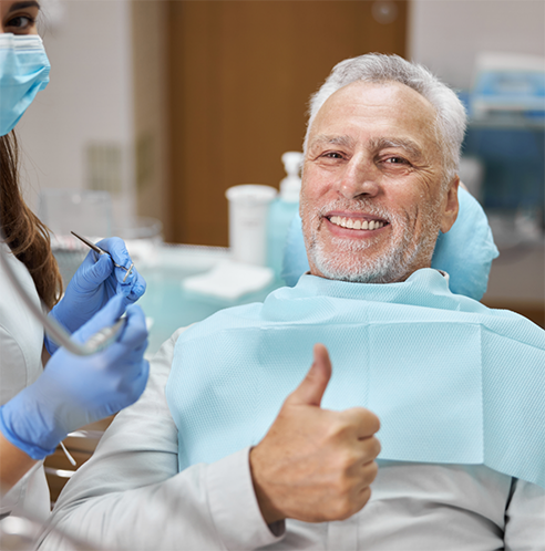 Male patient in dental chair giving thumbs up
