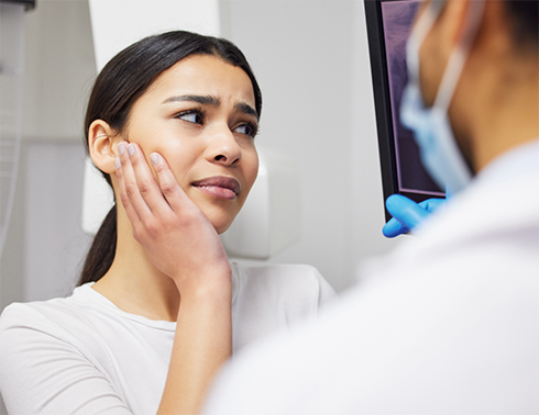 Close up of woman with ponytail rubbing jaw in pain