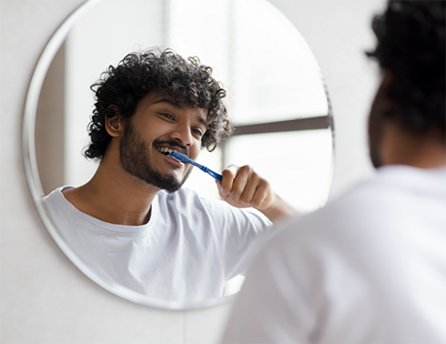 Man in white shirt brushing his teeth