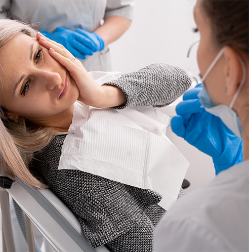 Dental patient with dental implant pain looking up at dentist