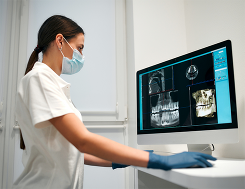 Dentist with mask looking at scans of teeth