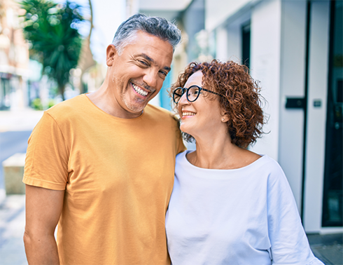 Man and woman side hugging while walking down street