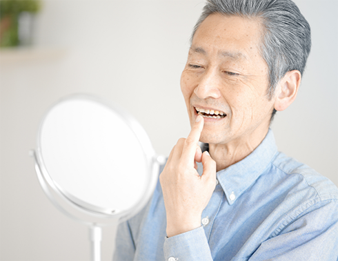 Older man checking teeth in mirror