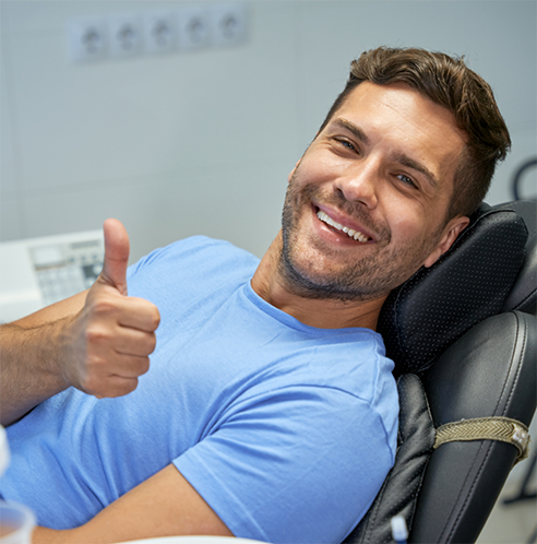 Male dental patient giving a thumbs up