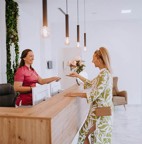 Female patient at front desk handing credit card to team member