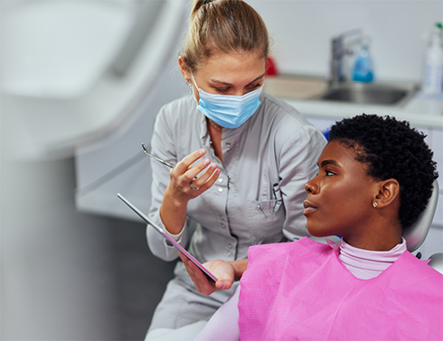Dentist with mask looking at young male patient