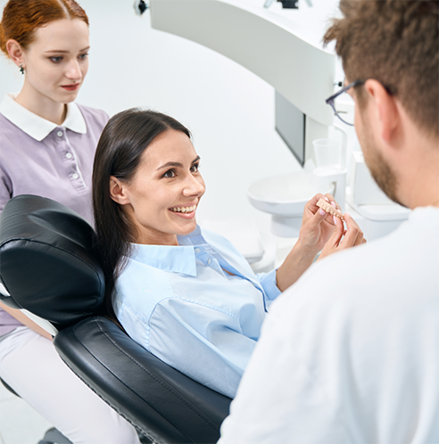 Female patient holding dental bridge and looking at dentist