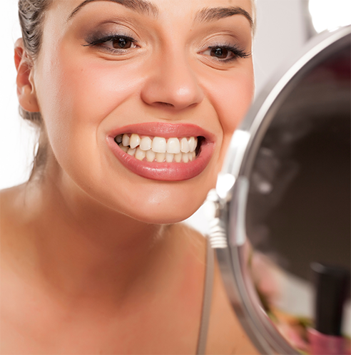 Woman checking teeth in mirror