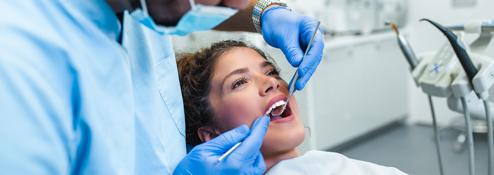 Female patient having teeth examined with dental instruments