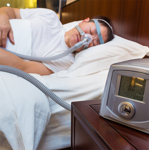 Man sleeping in bed while hooked up to CPAP machine