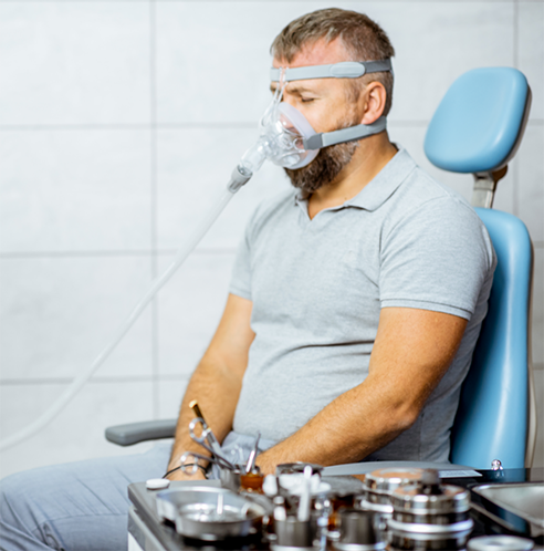Bearded man hooked up to CPAP machine while sitting in dental chair