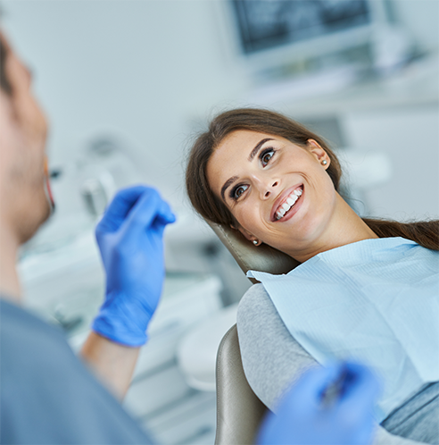 Female patient smiling up at dentist with gloves