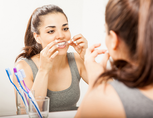 Woman using take-home teeth whitening strip