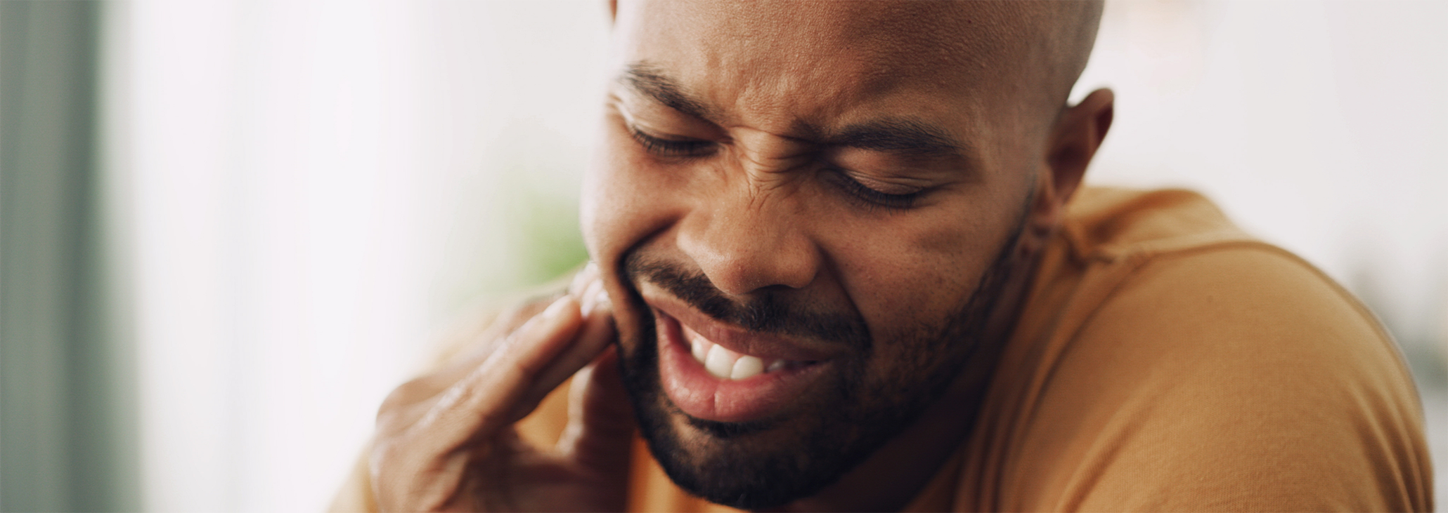 Close up of bearded man rubbing jaw in pain