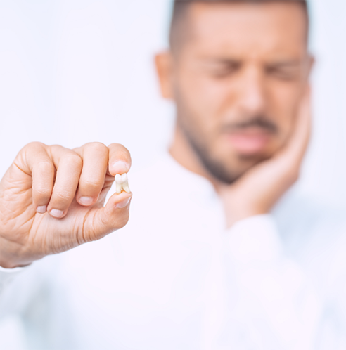 Man with jaw pain holding an extracted tooth