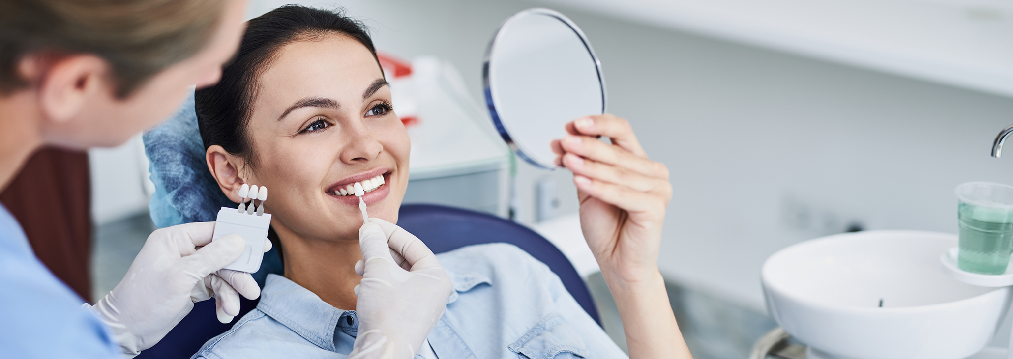 Female patient holding up mirror to check smile