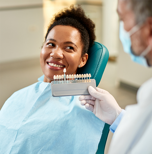 Patient smiling up at dentist while having teeth shade matched