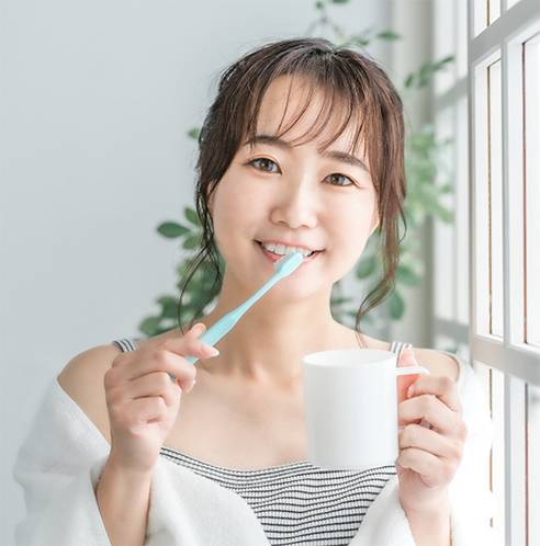 Woman brushing teeth and holding a mug