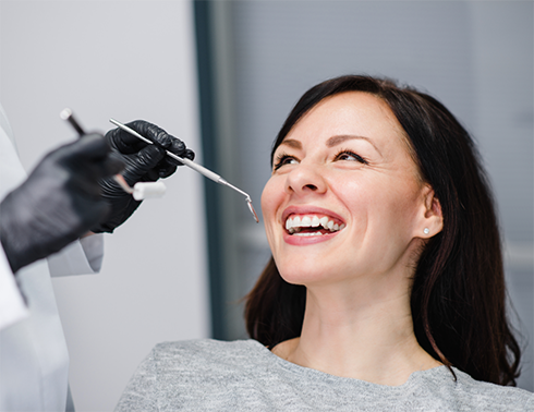 Woman laughing while dentist is preparing to examine teeth