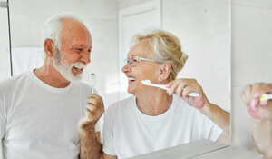 two older people brushing their implant dentures