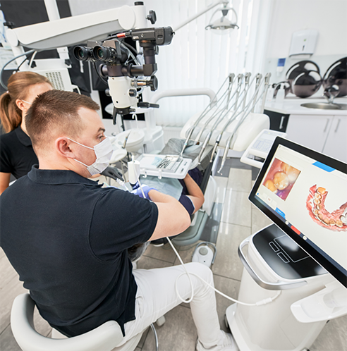 Dentists with masks looking at scans of teeth on monitor