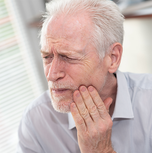 Bearded man rubbing jaw in pain